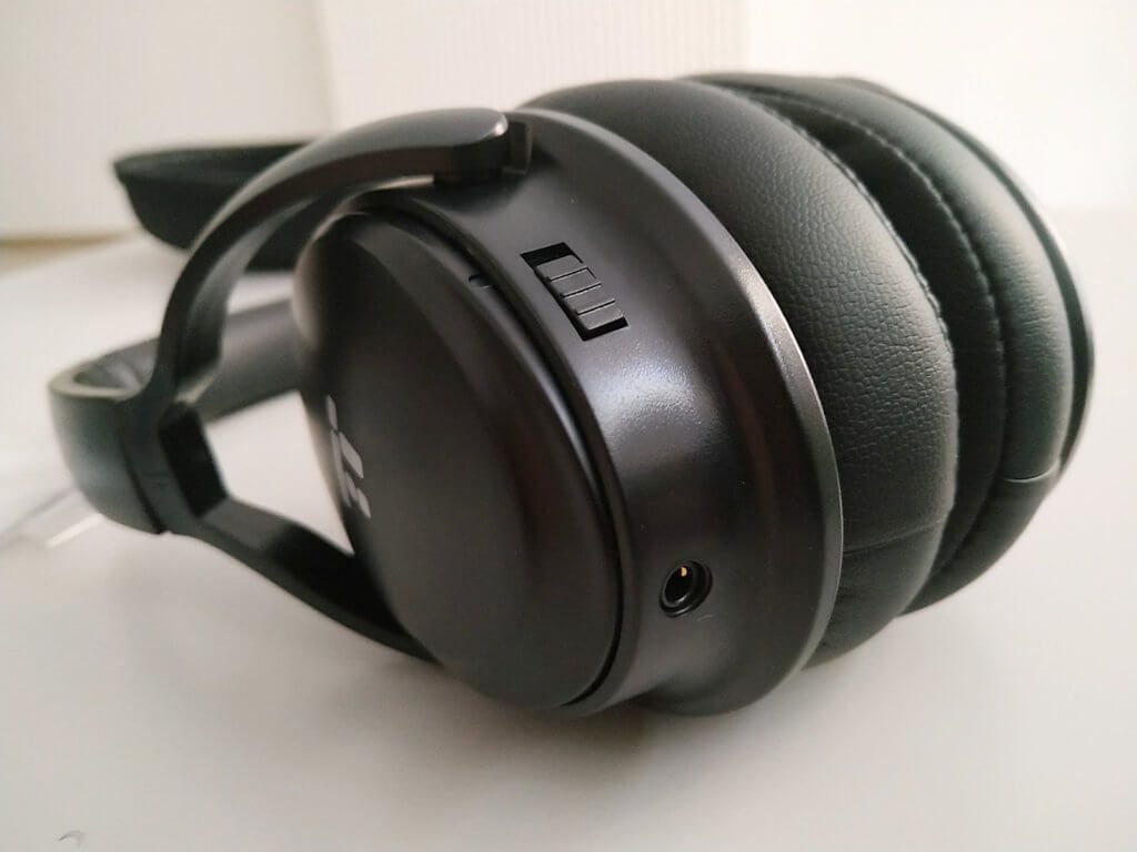 Mit dem Schalter lässt sich das Active Noise Cancelling zuschalten. Darunter befindet sich die Klinkenbuchse für die Verwendung als kabelgebundene Kopfhörer.