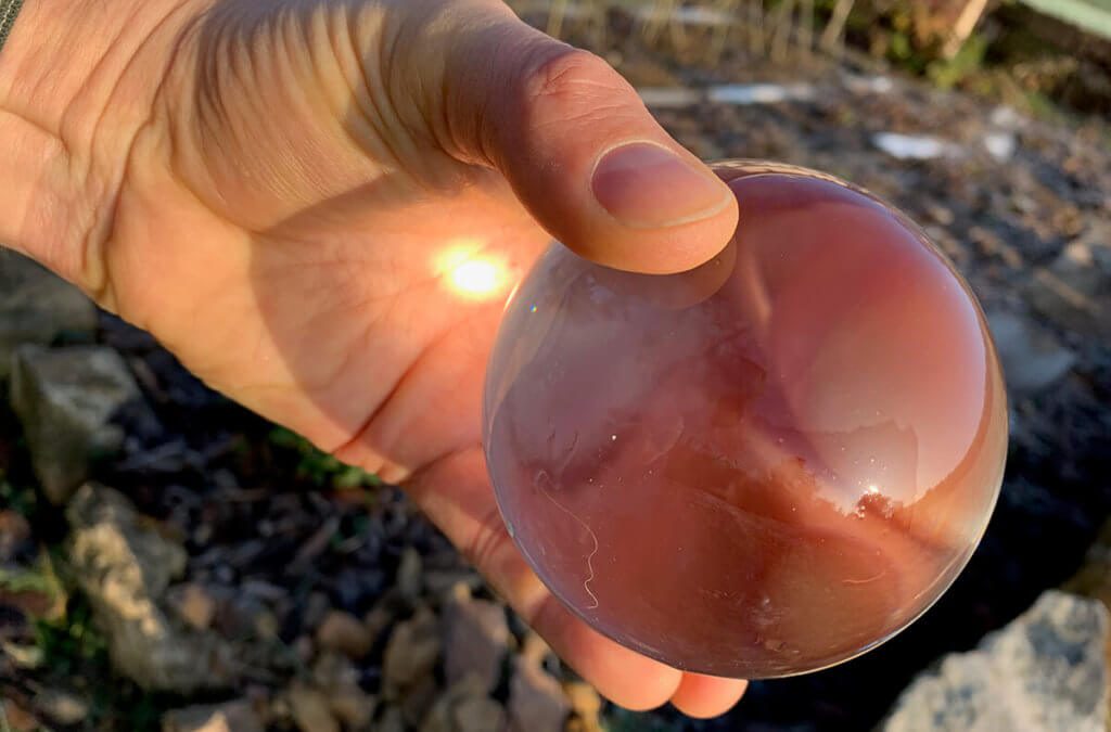 Hier sieht man gleich zwei Punkte auf die man beim Fotografieren mit einem Lensball achten muss: Zum einen, dass man sich kein Loch in die Handfläche brennt und zum anderen, dass man die Glaskugel immer schön putzt, bevor man Fotos macht.