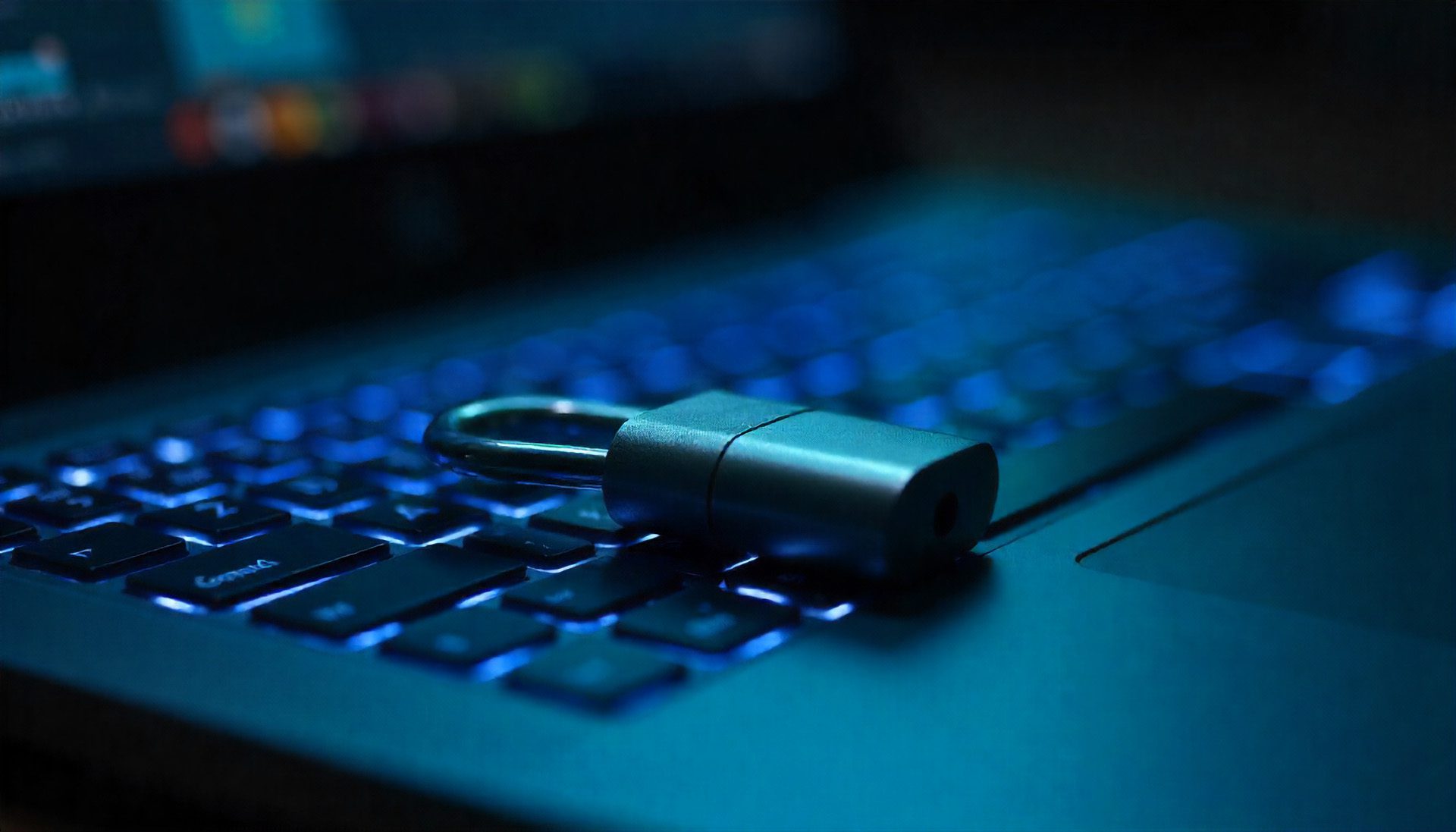 Metallisches Vorhängeschloss auf beleuchteter Laptop-Tastatur